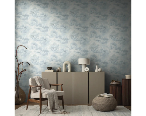 Obývacia izba s tapetou so vzorom oblakov, kreslom, komodou a dekoratívnymi prvkami pre útulnú atmosféru