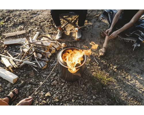 Ľudia sedia okolo ohniska a opekajú si marshmallows