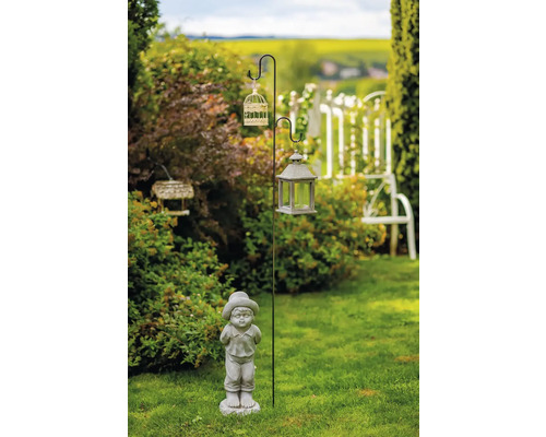 Záhradná scéna s ozdobným stĺpom, vtáčou klietkou, lampášom a figúrkou chlapca