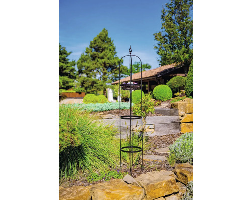 Kovová podpera pre rastliny s tromi policami v záhrade.