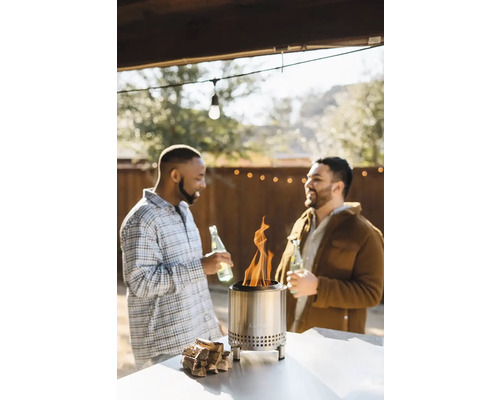 Dvaja muži sa rozprávajú vonku pri ohnisku s drevom.