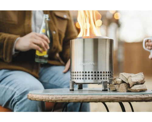 Kovové ohnisko s drevom na stole vonku