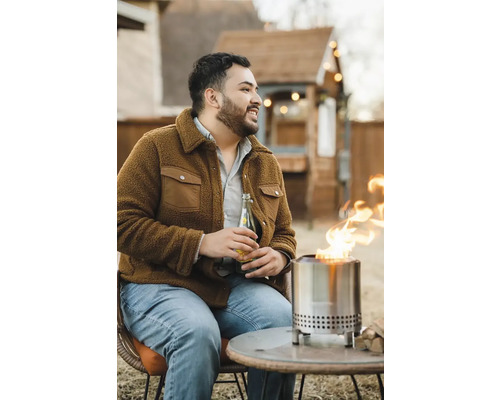 Scéna s mužom sediacim vonku pri bezdymovom ohnisku