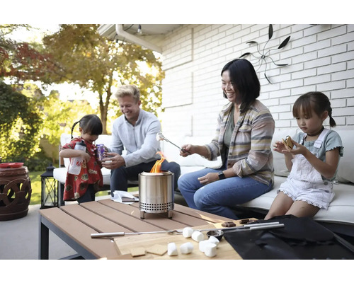 Rodina opeká marshmallows nad vonkajším ohniskom na terase.