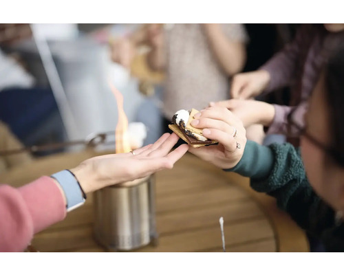 Ľudia si pripravujú marshmallows nad stolným grilom, aby si urobili s''mores