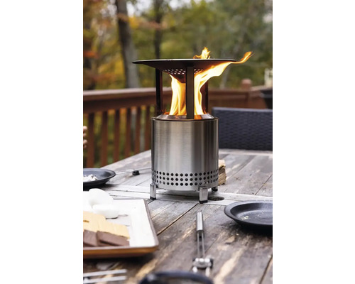 Kovové ohnisko na drevenom stole s ohňom a jedlom