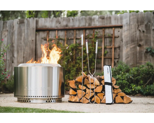 Ohnisko Solo Stove s ohňom, polenami a príslušenstvom v záhrade