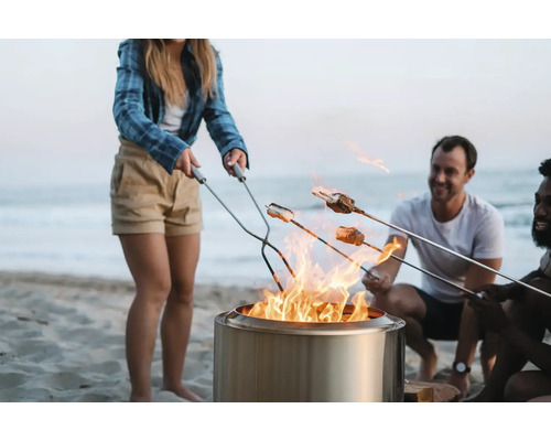 Ľudia opekajú marshmallows nad ohniskom na pláži.