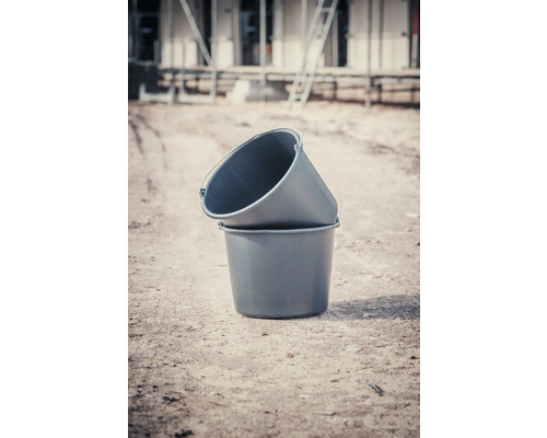 Dve plastové vedrá na maltu naskladané na seba na stavenisku.