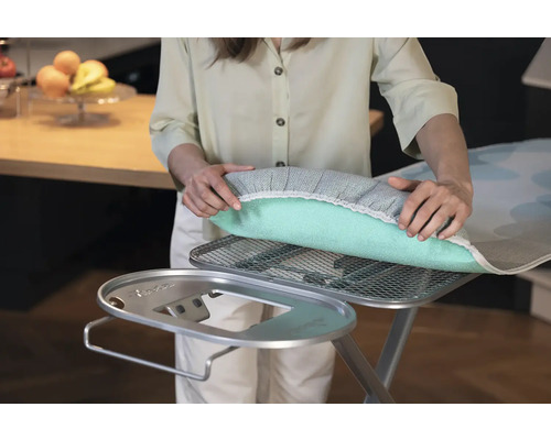 Žena kladie poťah na žehliacu dosku na žehliacu dosku