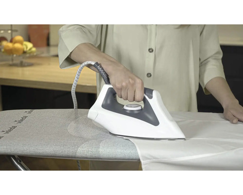 Osoba žehlí bielu košeľu žehličkou na žehliacej doske.