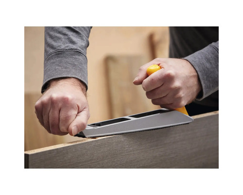 Osoba používa hoblík na opracovanie kusu dreva.