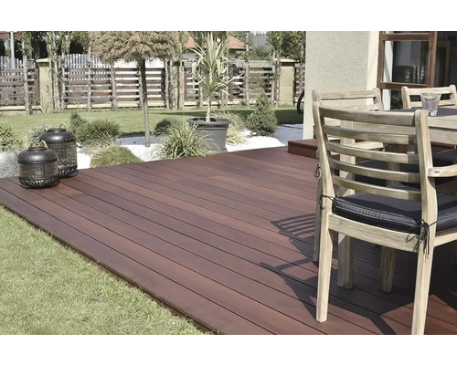 Terasa s drevenými doskami, záhradným nábytkom a dekoratívnymi lampášmi v záhrade