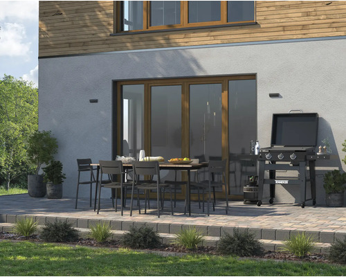 Terasa s grilom, záhradným stolom a záhradnými stoličkami pred stenou domu