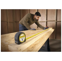 Zvinovací meter Stanley Tylon s pracovníkom merajúcim kus dreva