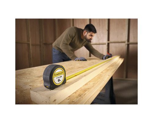 Zvinovací meter Stanley Tylon s pracovníkom merajúcim kus dreva