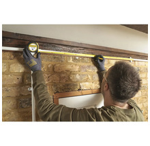 Osoba meria dĺžku steny pomocou zvinovacieho metra.