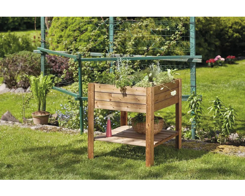 Drevený vyvýšený záhon s rastlinami a policou v záhrade