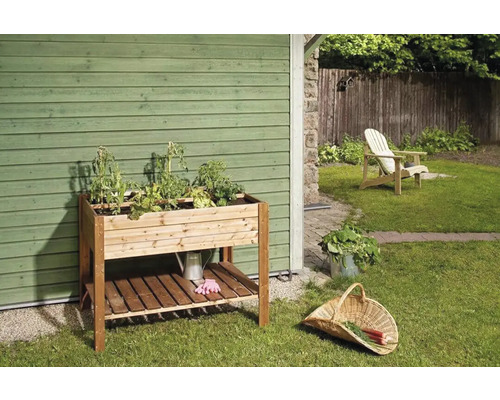 Drevený pestovateľský stôl s rastlinami a záhradným príslušenstvom v záhrade