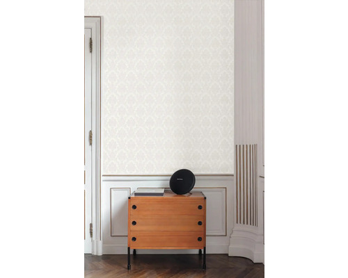 Scéna s komodou, reproduktorom a vzorovanou tapetou vo svetlej miestnosti