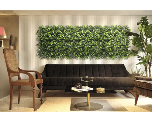 Dekoratívny interiér s rastlinným nástenným panelom nad čiernou pohovkou.