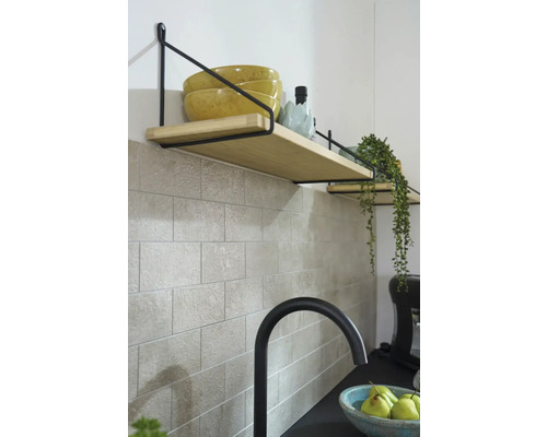 Police s drevenými doskami a čiernym držiakom na obkladanej stene v kuchyni.