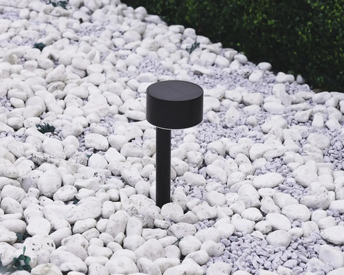 Čierne solárne svietidlo v záhrade medzi bielymi kameňmi