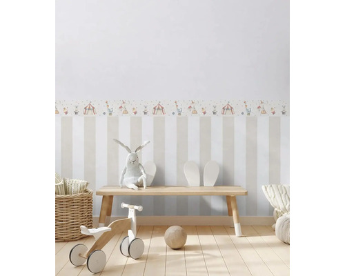 Detská izba s pruhovanou tapetou a bordúrou s motívom cirkusu, s drevenou lavicou, hračkami a dekoráciou