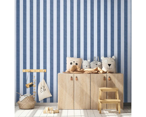 Detská izba s pruhovanou tapetou, drevenou komodou a hračkami.