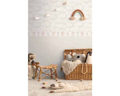 Detská izba s tapetou s motívom oblakov, hračkami a ratanovým nábytkom pre útulnú atmosféru