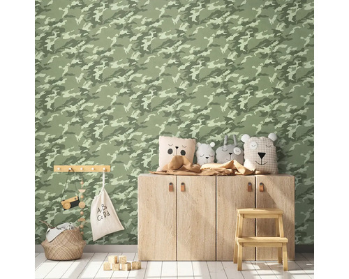 Zdobená detská izba s tapetou so vzorom kamufláže, drevenou skrinkou, ozdobnými vankúšmi, úložným košom a hračkami