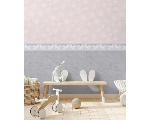 Detská izba s ružovou tapetou, hračkami a malou drevenou lavicou.