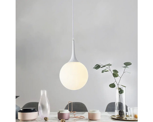 Závesná lampa s guľatým skleneným tienidlom nad jedálenským stolom