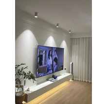 Obývacia izba so stropnými svietidlami, televízorom a bielym nábytkom