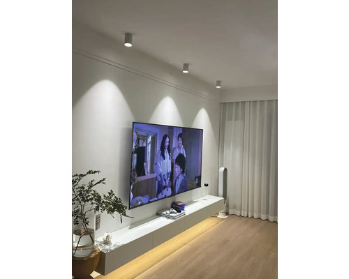 Obývacia izba so stropnými svietidlami, televízorom a bielym nábytkom