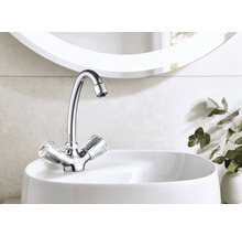 Lesklá vodovodná batéria s priehľadnými rukoväťami na bielom umývadle