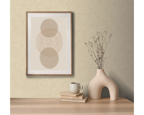 Dekoratívna scéna s abstraktným umeleckým dielom v ráme, vázou s kvetmi, knihami a šálkou na stole.