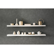 Dve biele nástenné police s dekoratívnymi predmetmi na tmavej stene