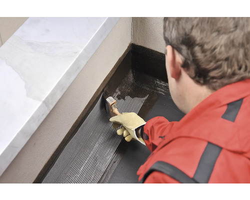 Osoba nanáša štetcom tesniacu hmotu na tkaninu