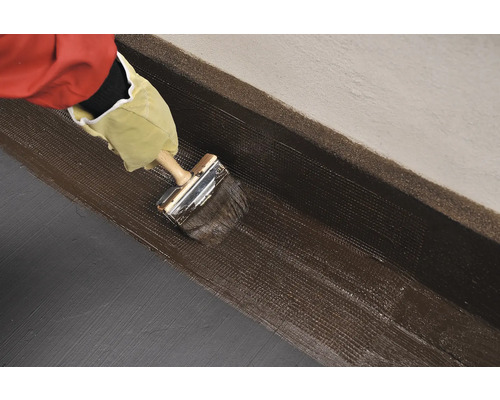 Nanášanie tesniaceho materiálu štetcom na stenu.