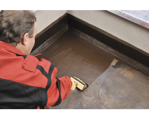 Remeselník nanáša štetcom hydroizoláciu na podlahu