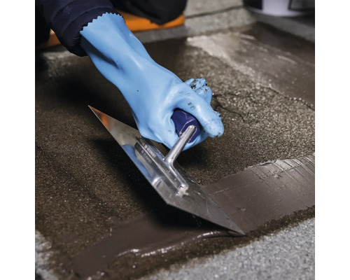 Osoba má rukavice a používa hladidlo na nanášanie náteru.