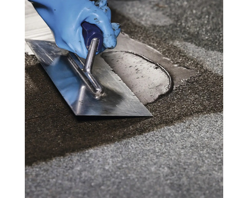 Remeselník vyhladzuje vyrovnávaciu hmotu stierkou