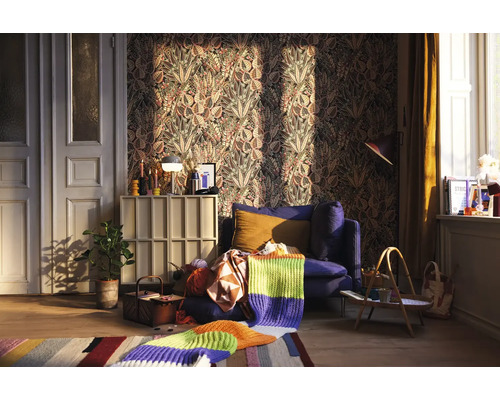 Obývacia izba so vzorovanou tapetou, modrým kreslom a pletenou dekou