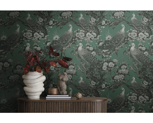 Izba s vzorovanou tapetou s pávmi a kvetmi, zdobená bytovými doplnkami na drevenom stole