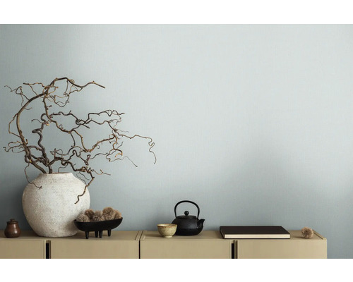 Dekoratívne vetvy vo váze vedľa čajovej kanvice na skrinke