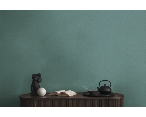 Detailný záber zelenej štruktúrovanej tapety nad stolom s dekoráciami.