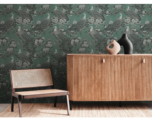 Obývacia izba so zelenou tapetou s motívom pávov, drevenou komodou a stoličkou s výpletom