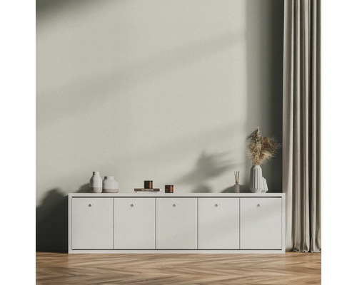 Obývacia izba s bielou komodou, dekoráciou a závesom na drevenej podlahe.