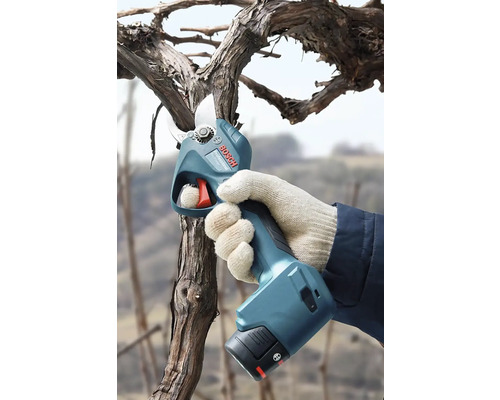 Ruka v rukavici strihá konár elektronickými nožnicami